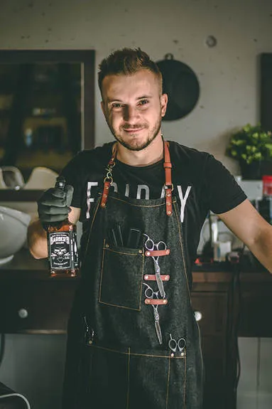 Toni mit Barberschürze und Scheren im Laden